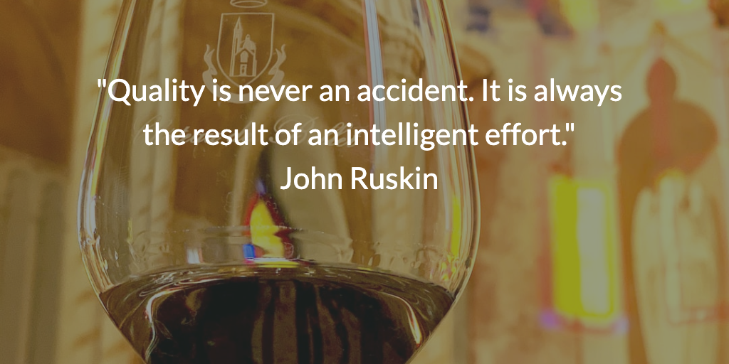 Close-up of a glass of fine wine with the John Ruskin quote 'Quality is never an accident. It is always the result of intelligent effort.